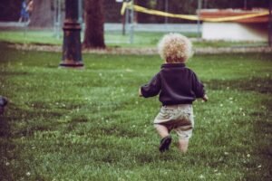 Toddler running in a meadow representing life lessons from children about happiness, presence, and personal growth
