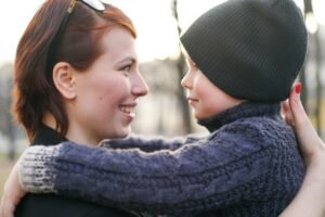 Mother and child at eye level, looking into each other’s eyes in a calm, connected moment that reflects emotional safety, trust, and steady parenting.