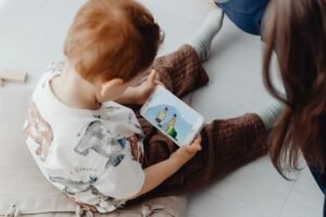 Toddler focused on a phone while a parent tries to talk, a common situation when kids ignore parents